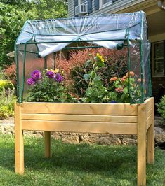 a wooden planter filled with lots of flowers in front of a house on the grass