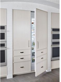 an open refrigerator door in a white kitchen