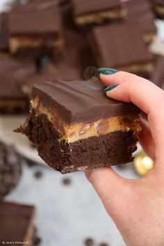 a hand holding a piece of chocolate peanut butter brownie