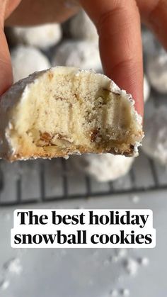 a hand holding a half eaten doughnut with the words, the best holiday snowball cookies