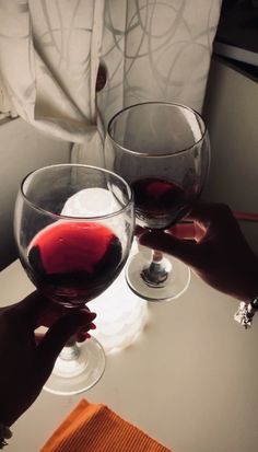 two people toasting with red wine in glasses