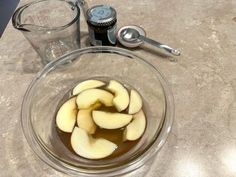 sliced apples in a glass bowl next to a blender and measuring cup on a counter