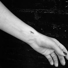 a person's hand with a small tattoo on the left wrist and an arrow in the middle