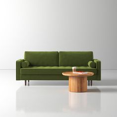 a green couch sitting next to a wooden table on top of a white flooring