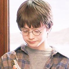 a young boy wearing glasses holding a cell phone