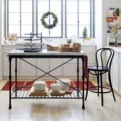 a kitchen with a table and chairs in front of a large window filled with christmas wreaths