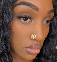 a close up of a woman with a nose ring on her nose and an earring in the shape of a flower