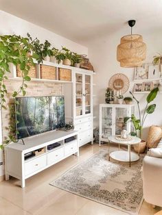 a living room filled with furniture and lots of greenery on top of the shelves