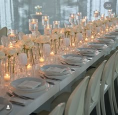 a long table is set with white flowers and candles for an elegant dinner or reception