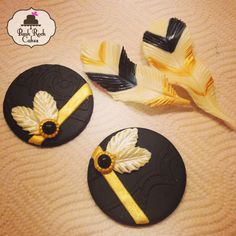 two black and yellow buttons with white flowers on them next to a feather ornament