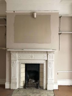 an empty living room with a fireplace and shelves