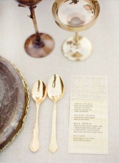 the table is set with gold utensils and menus