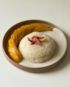 a white plate topped with rice and sliced mangoes next to a banana wedge on top of it