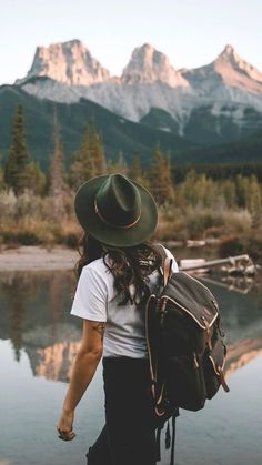 a person with a hat and backpack walking by water