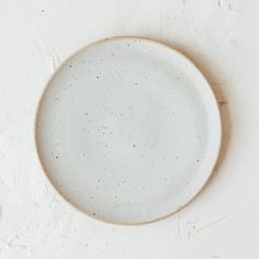 a white plate with speckles on it sitting on a table next to a wall