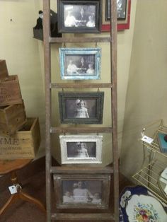 an old wooden ladder with pictures on the top and bottom shelves in front of it