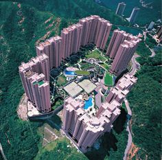 an aerial view of a high rise building in the middle of a green area with swimming pools