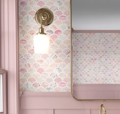 a bathroom with pink and gold wallpaper and a large mirror over the sink that's mounted on the wall