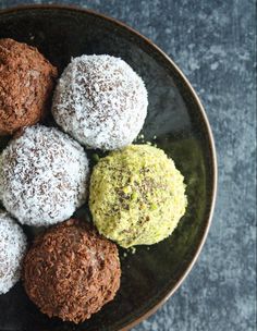 four different types of chocolate truffles on a black plate with sprinkled powdered sugar