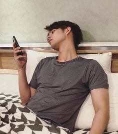 a man laying in bed while holding a cell phone