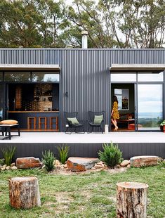 a person standing on the porch of a modern house with large windows and sliding glass doors