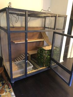 a large cage with plants inside of it on the floor in front of a door