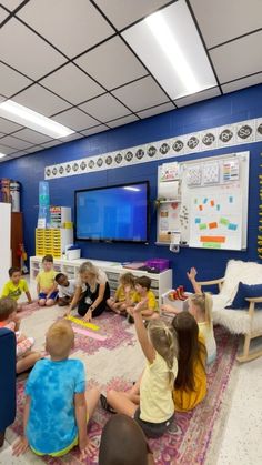 a group of children sitting on the floor in front of a tv