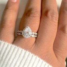 a woman's hand with a diamond ring on it and a white sweater in the background