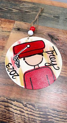 a wooden ornament with an image of a person wearing a red hat on it