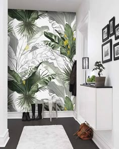 a room with a white rug and wallpaper that has green tropical leaves on it