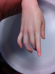 a close up of a child's hand on a toilet seat lid with his fingers