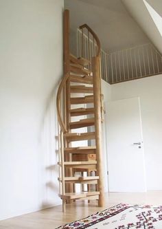 a wooden spiral staircase in the corner of a room with a rug on the floor