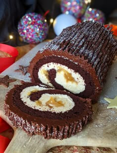 there is a chocolate roll on the cutting board with icing and sprinkles