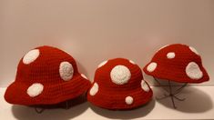 two crocheted hats with white polka dots on them sitting on a shelf next to each other