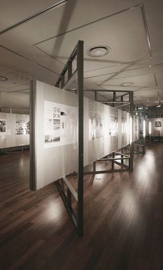 an empty room with wooden floors and pictures on the wall, in front of glass partitions