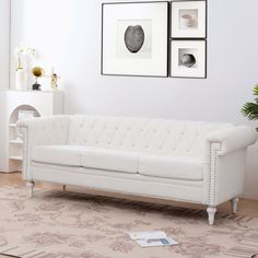 a white couch sitting in a living room next to two framed pictures on the wall