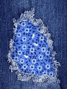 a piece of blue fabric with white flowers on it and frayed edges in the middle