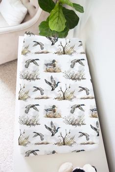 a stuffed animal sitting next to a sheet with birds on it