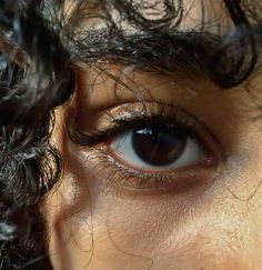 a close up of a person's eye with curly hair