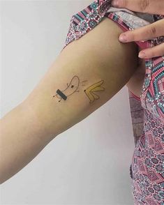 a woman's arm with a small cartoon character tattoo on the left inner arm