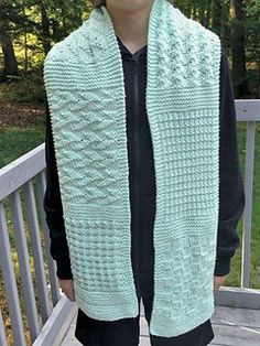 a woman standing on a porch wearing a green knitted scarf