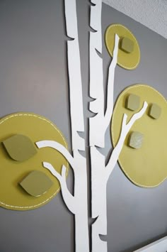 a white tree with yellow leaves is on the wall next to a gray painted door