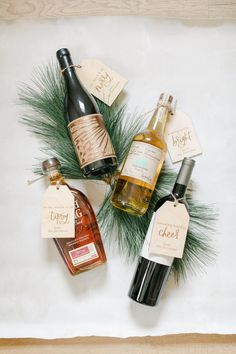 several bottles of wine sitting on top of a wooden table next to pine cones and tags