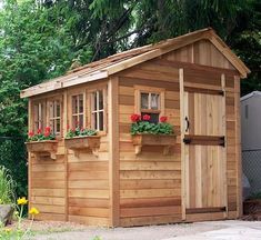 a small wooden shed with flower boxes on the roof and windows in it's side