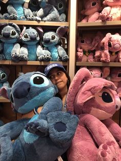 a woman holding two large stuffed animals in front of shelves filled with other stuffed animals