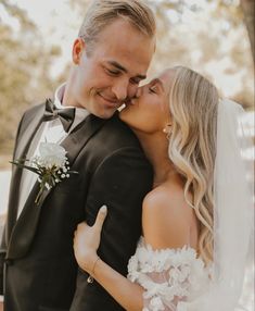 a bride and groom kissing each other outside