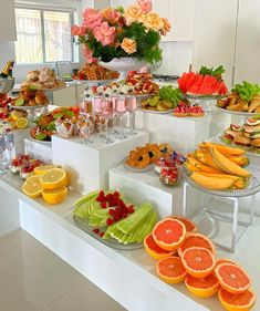 an assortment of fruits and pastries on display in a buffet style setting with flowers