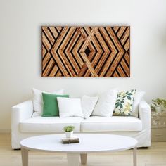 a living room with a white couch and wooden wall art on the wall above it