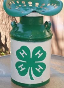 a green and white canister sitting on top of a table next to a fence