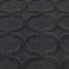 a black rug with circles on it in the middle of an area that looks like carpet